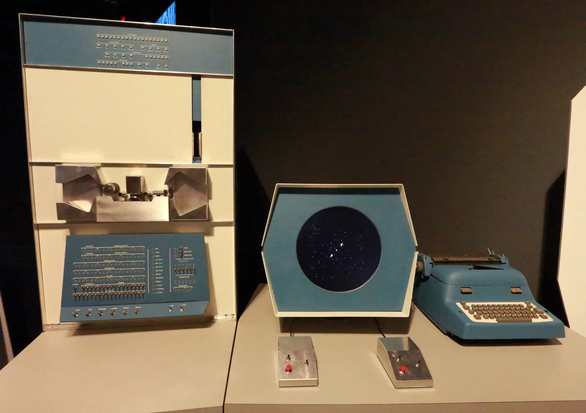 Ein großes, weiß-blaues DEC PDP-1-Computersystem, auf dem das Spiel Spacewar läuft, bestehend aus Hauptrechner, Monitor und Steuerkonsolen.